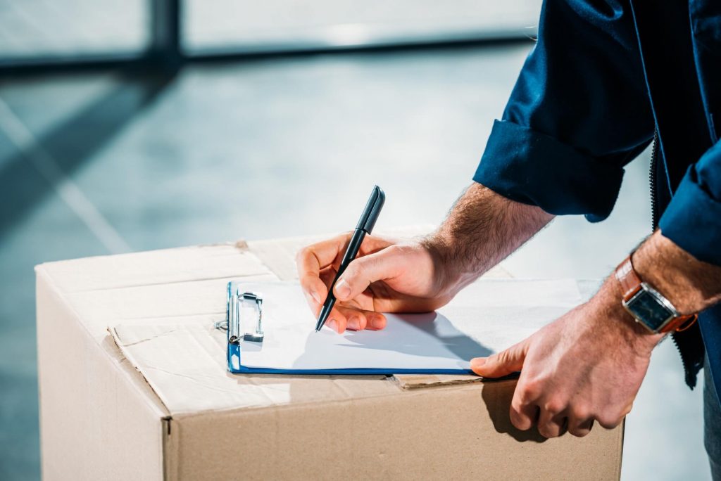 Courier filling cargo declaration on cardboard package